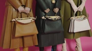 Three fashion models showcase handbag accessories in front of a hot pink backdrop, featuring various colored coats and boots.