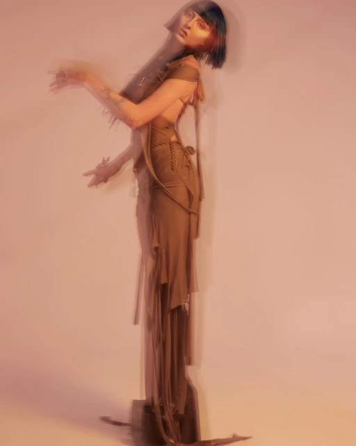 A blurry fashion shot featuring a woman in a green dress, posing in a studio environment with soft lighting, creating an artistic and ethereal feel.