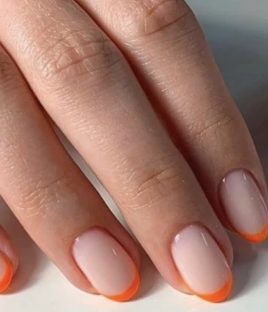 Close-up of a person's hand displaying manicured fingernails with a trendy orange-tipped French manicure. Beauty and nail design.