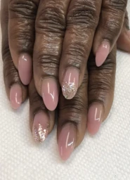 Close-up of almond-shaped nude pink manicured nails with glitter accent details by nail artist Cenita Scott