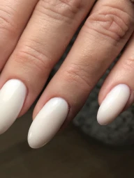 Close-up of human fingers showcasing clean almond-shaped white gel manicure by nail artist Cenita Scott.