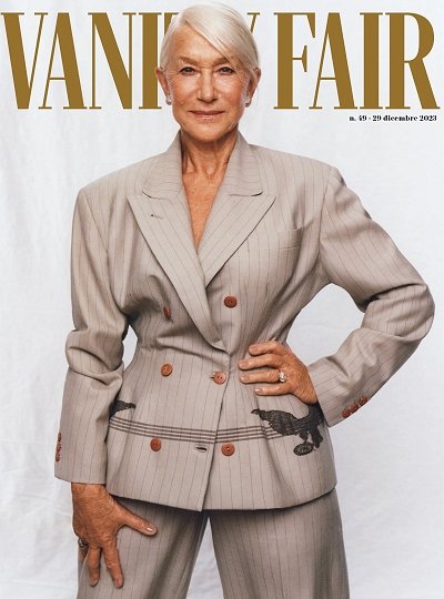 Helen Mirren is on the cover of Vanity Fair, wearing a beige striped suit with bird embroidery, posing in a studio environment.