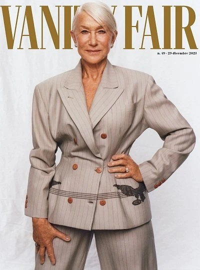 Helen Mirren is on the cover of Vanity Fair, wearing a beige striped suit with bird embroidery, posing in a studio environment.