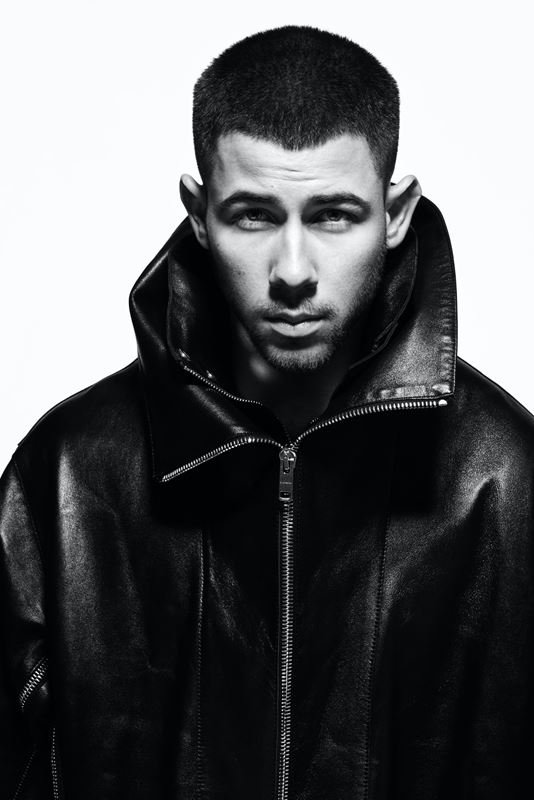 Portrait of a man in a black leather jacket against a white background, captured in a medium shot with sharp focus.