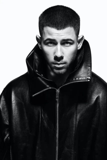 Portrait of a man in a black leather jacket against a white background, captured in a medium shot with sharp focus.