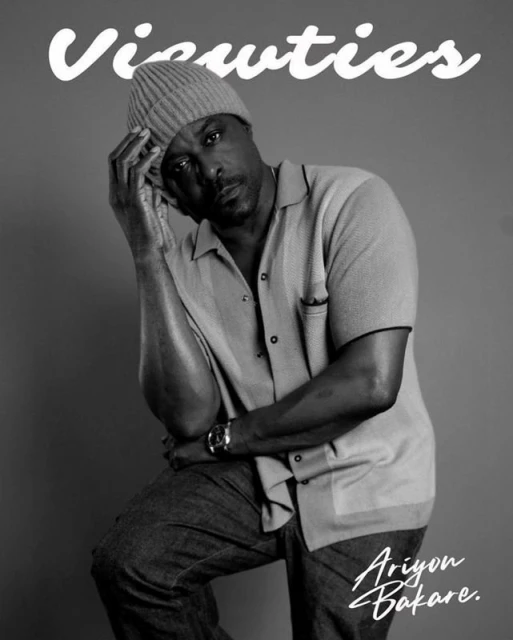 Monochrome portrait of a man in a beanie and button-down shirt, seated in a studio with the magazine title 'Viewties' displayed above him.