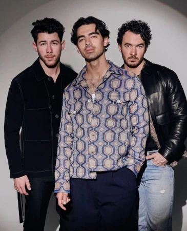 Three men posing together against a plain grey seamless background, styled by hair stylist Charley Mcewen in London.