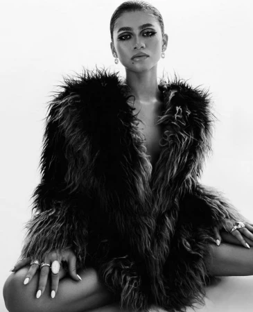 Zendaya wearing a shaggy faux fur coat and statement rings against a white background