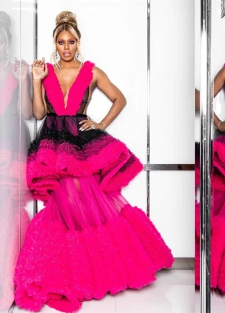 Elegant adult woman with blonde hair in a hot pink and black gown posing indoors with a confident expression and jewelry.