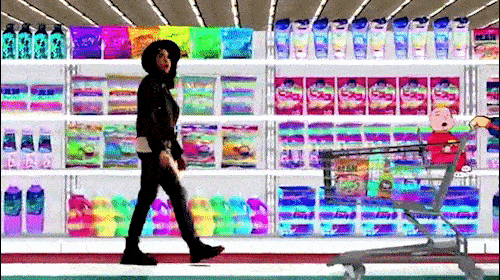 Young woman in a black jacket walks past supermarket shelves, pushing a shopping cart with a child sitting in it, brightly lit interior.