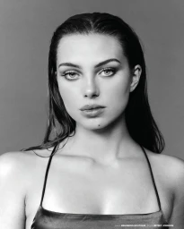 Black and white close-up portrait of a woman with dark wet-look hair wearing a thin-strap dress.