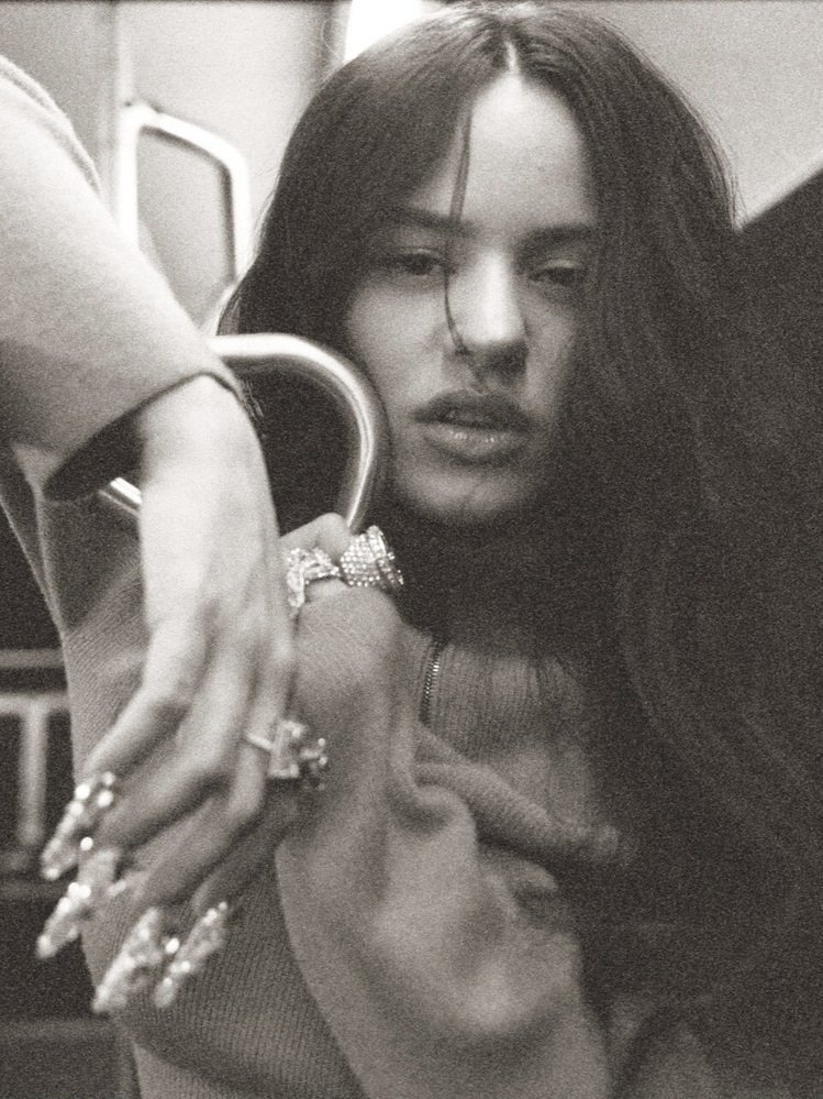 Close-up shot of a woman with long, dark hair and elaborate rings posing indoors, monochromatic color palette, jewelry fashion