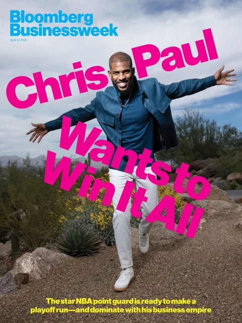 Magazine cover of NBA player Chris Paul outdoors, wearing a blue jacket and white pants, set against a desert landscape.