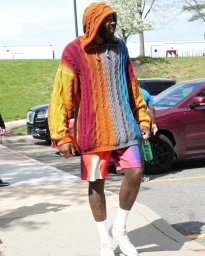 Man wearing a colourful cable-knit hoodie and patterned shorts walking outdoors in Los Angeles