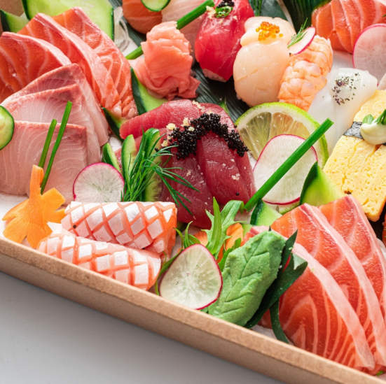 Assorted sashimi and sushi on a wooden tray, featuring salmon, tuna, and other fresh seafood with radish and greens garnish.