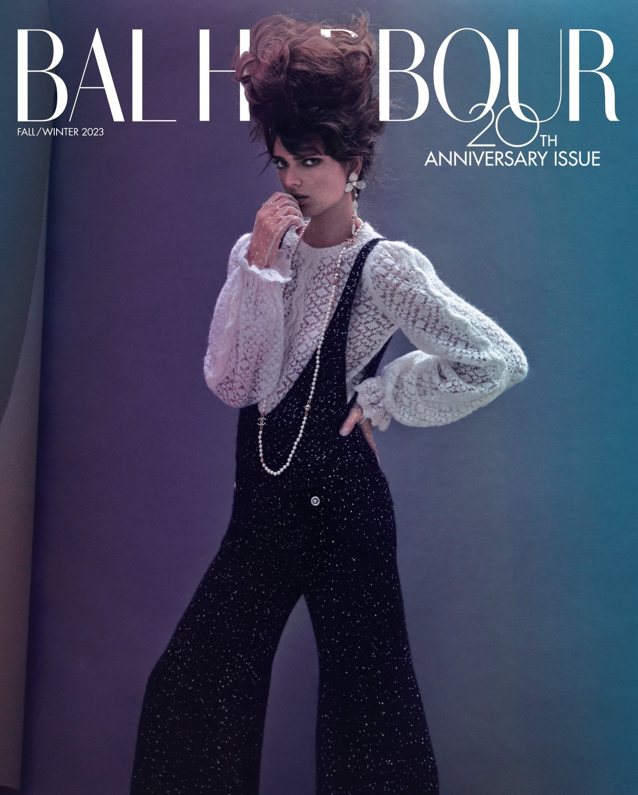 Magazine cover featuring a woman with elaborate hair wearing a lace top and black jumpsuit against a blue and purple gradient backdrop.