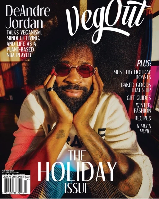 VegOut magazine cover featuring DeAndre Jordan with an afro and red-tinted glasses. He wears a cream sweater while posing with his hands.