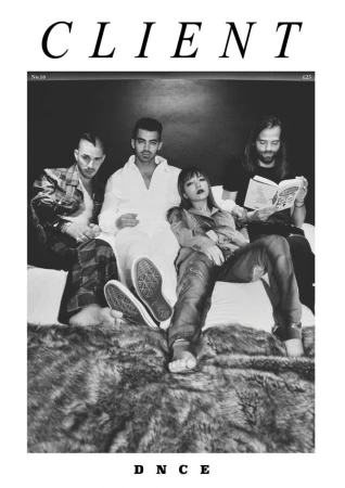 Black and white image features four young adult band members sitting on a fur-covered bed, one reading, in a magazine cover style.