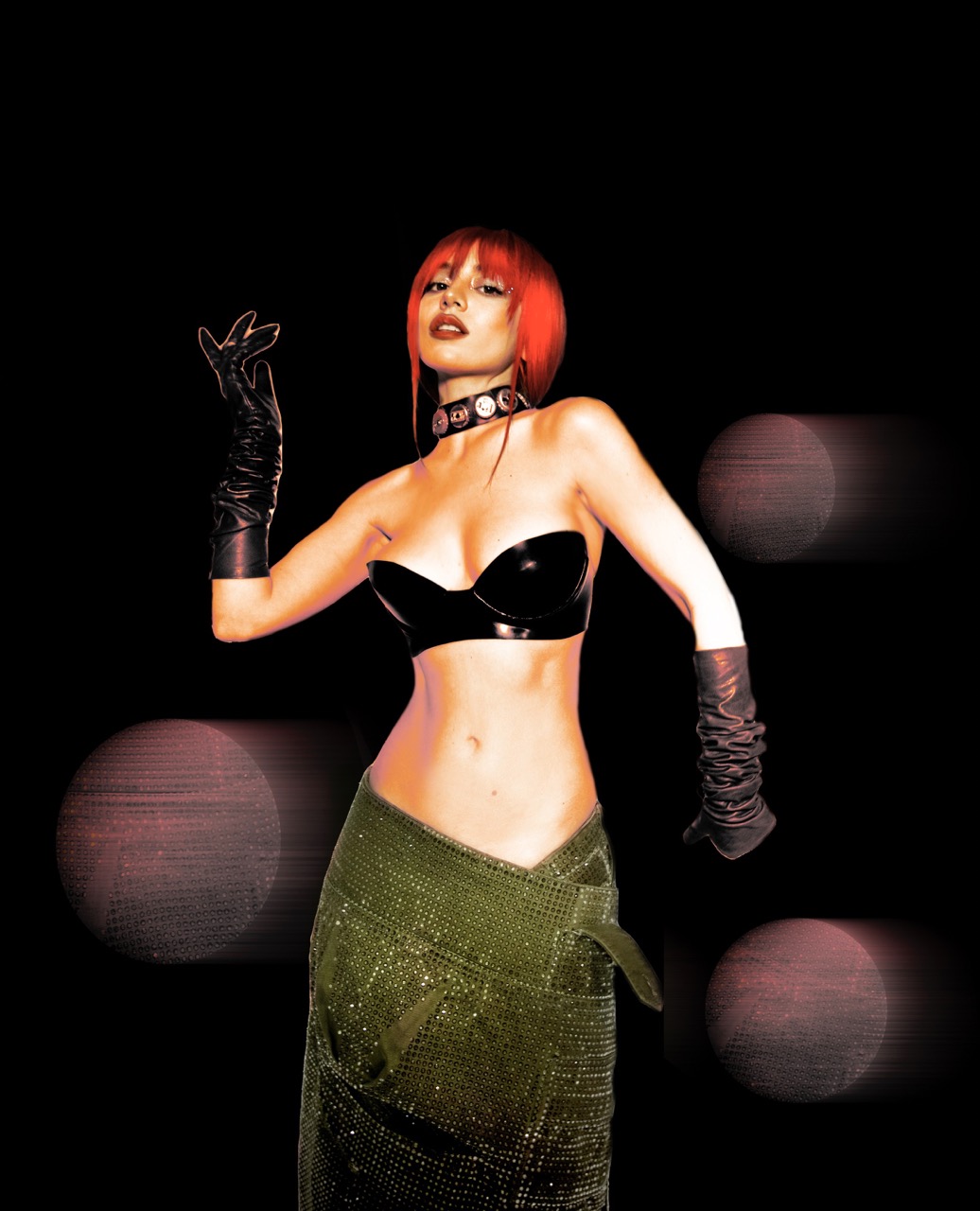 A slender woman with red hair poses in a black bra, shiny green skirt and long black gloves against a dark background with pink orb effects.