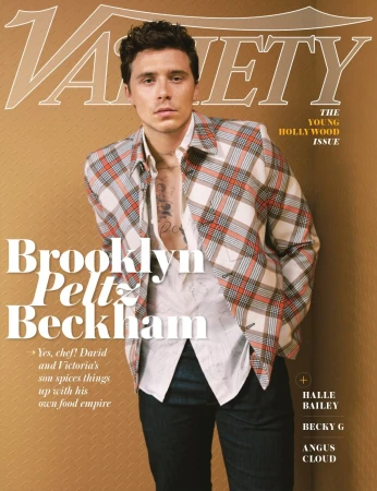 Brooklyn Peltz Beckham wearing an unbuttoned plaid jacket and white shirt against a textured brown background