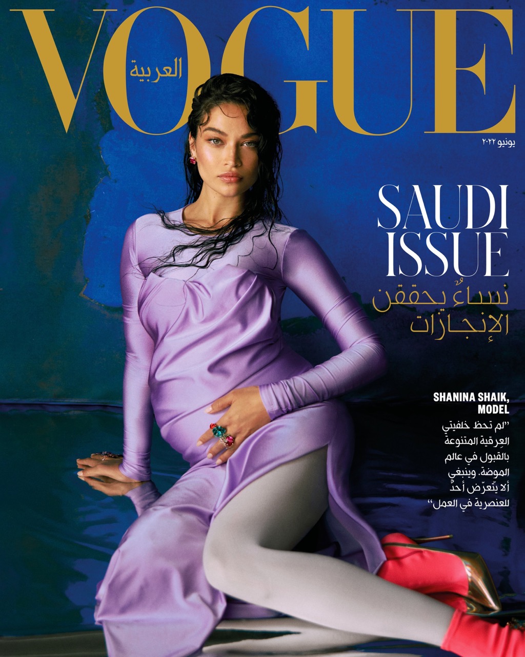 Vogue Arabia cover featuring model Shanina Shaik in a lilac dress and pink high heels, sitting against a dark blue background.