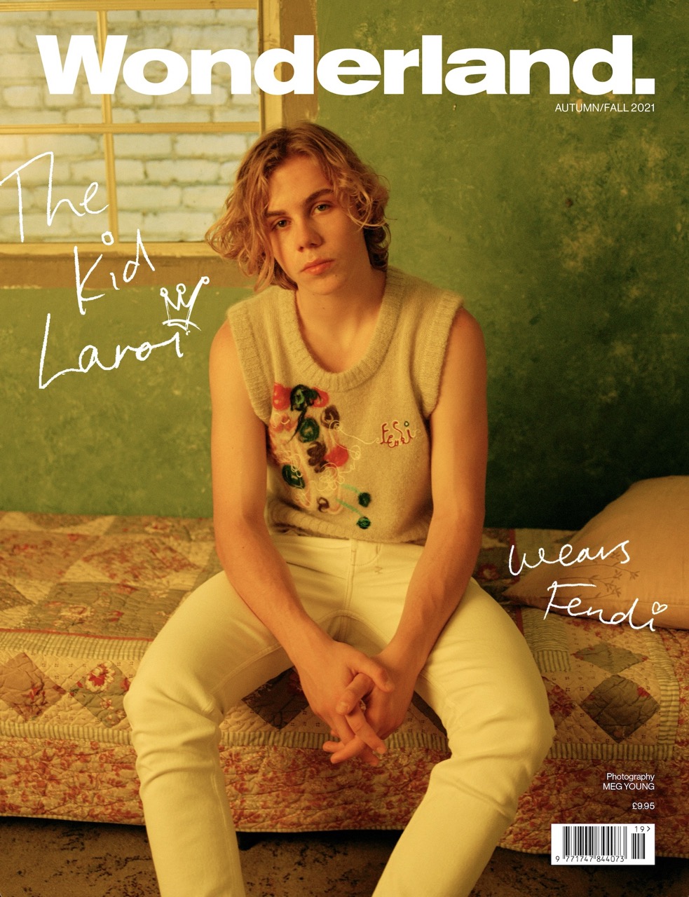 Magazine cover featuring a person seated indoors wearing a sweater vest and light pants, showcasing fashion and editorial style.