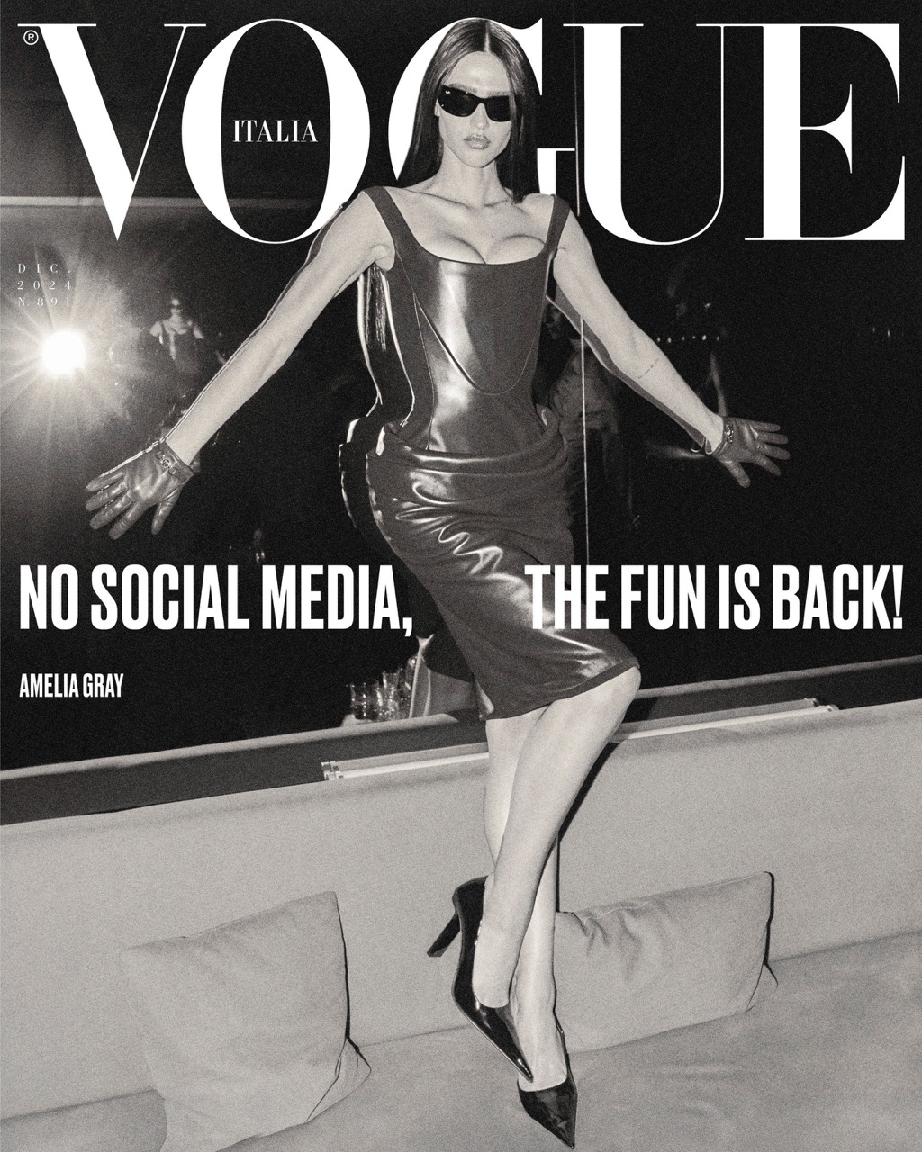 Vogue Italia cover featuring Amelia Gray in a shiny black dress, high heels, and sunglasses striking a pose with outstretched arms.