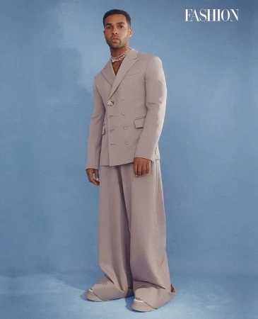 Man wearing a tailored lavender double-breasted suit and wide trousers against a blue background