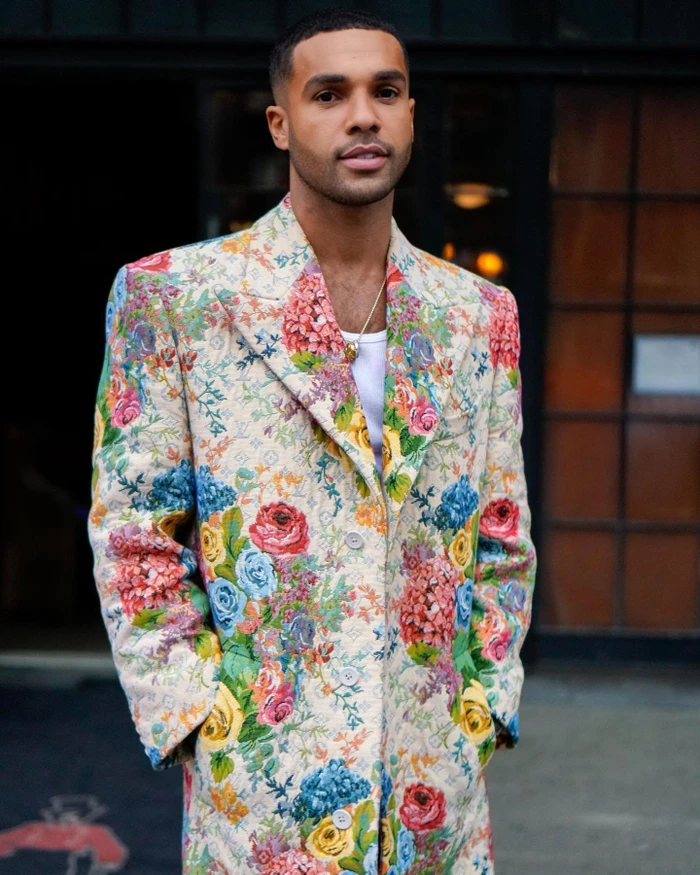 Man wearing a cream floral patterned coat with pink, yellow, and blue flowers over a white tank top, styled by Danyul Brown.
