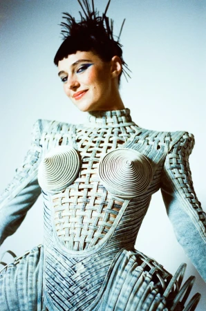 Model wearing a structured woven architectural outfit with cone accents and spiky dark hair by Danyul Brown.