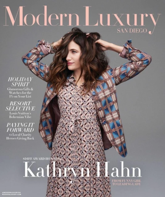 Kathryn Hahn on the cover of Modern Luxury San Diego magazine, wearing a patterned dress and jacket, with her hands in her hair.