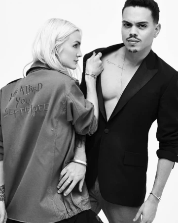 Black and white portrait of a blonde woman wearing an embroidered jacket and a man in an open black blazer by Denis De Souza