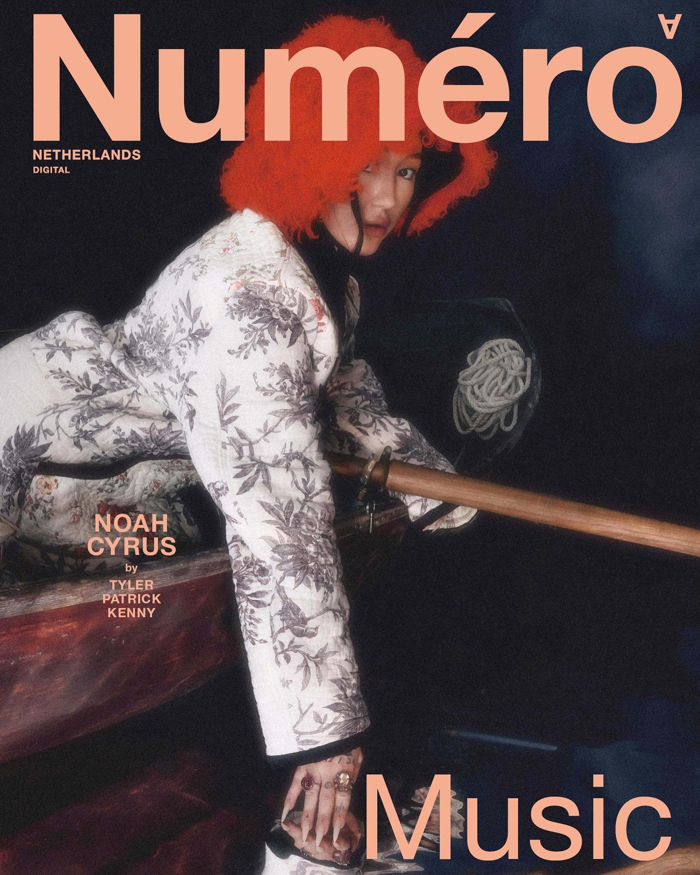 Numero Netherlands magazine cover featuring Noah Cyrus wearing a patterned jacket and coral hat in front of a dark backdrop.