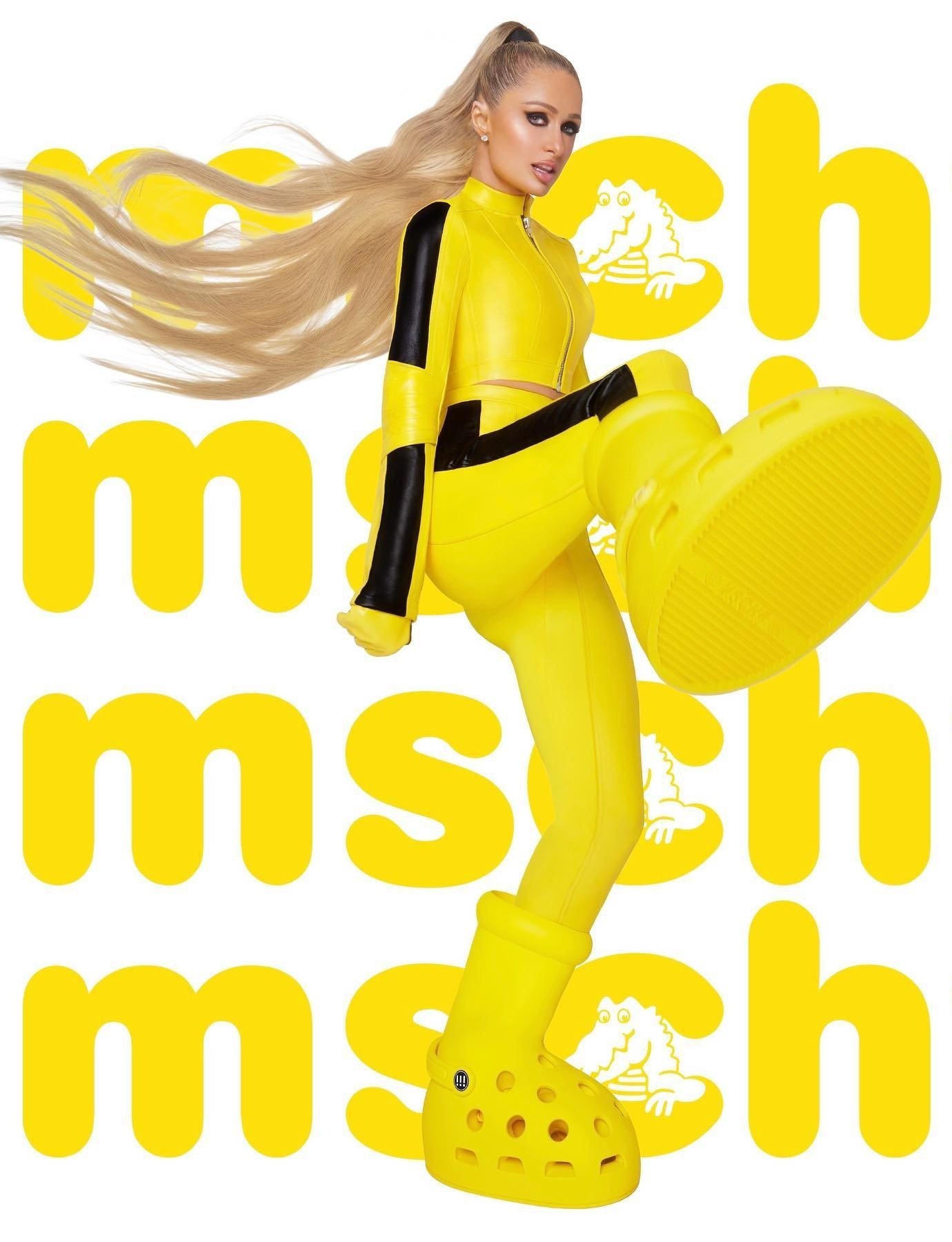 Paris Hilton poses in bright yellow outfit and oversized Crocs, a fashion-forward and playful image against a logo background.