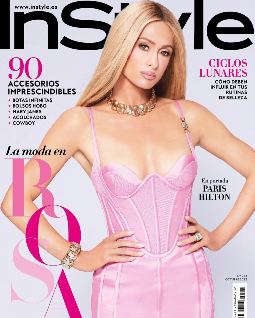 Magazine cover featuring Paris Hilton in a pink dress, adorned with a gold necklace and bracelet, against a light background. 