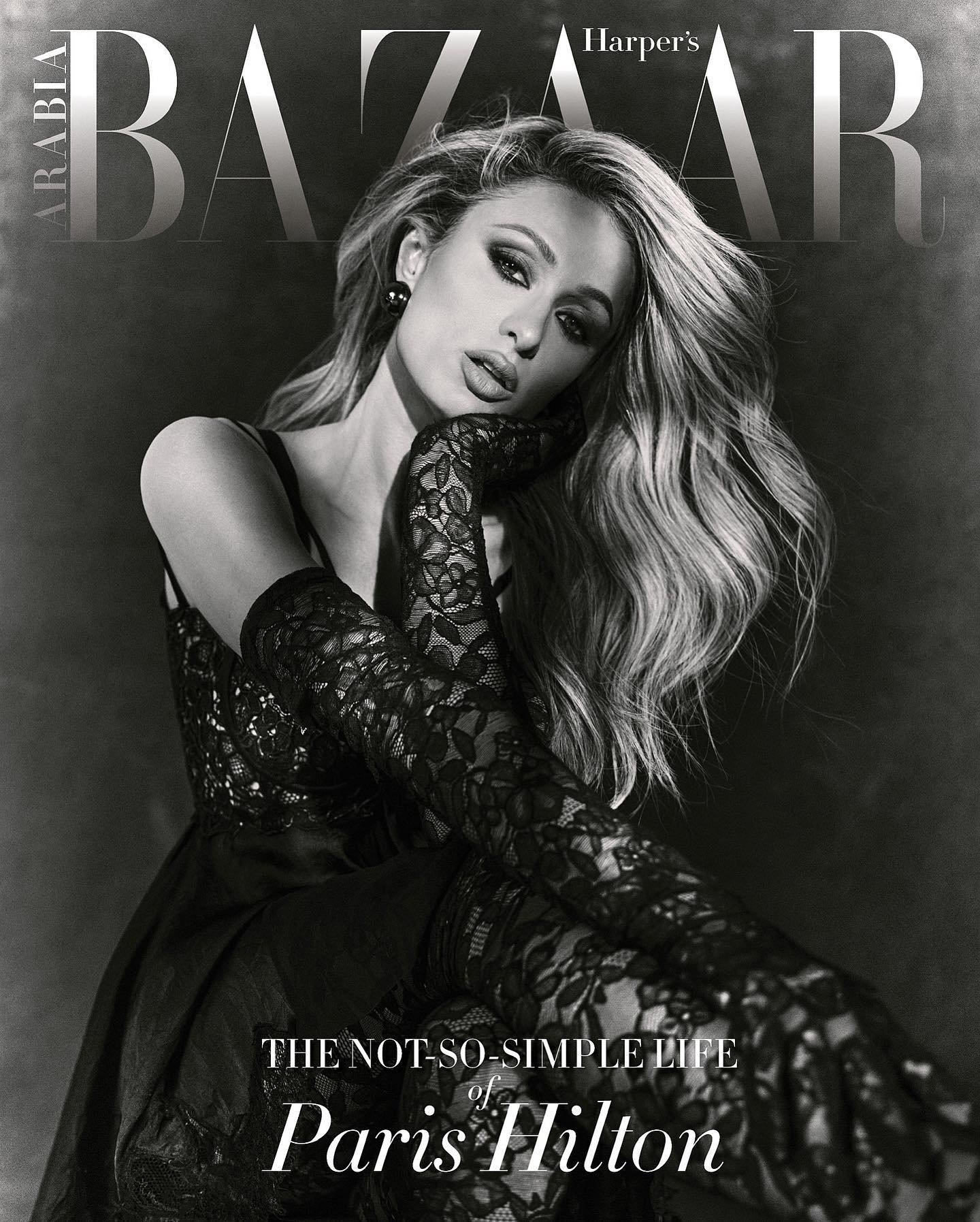 Paris Hilton poses in a black dress and lace gloves for a Harpers Bazaar Arabia cover. She has blonde hair and wears smokey eye makeup.