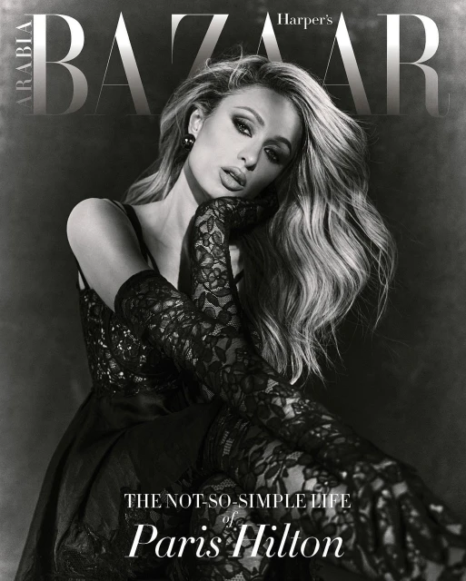 Paris Hilton poses in a black dress and lace gloves for a Harpers Bazaar Arabia cover. She has blonde hair and wears smokey eye makeup.