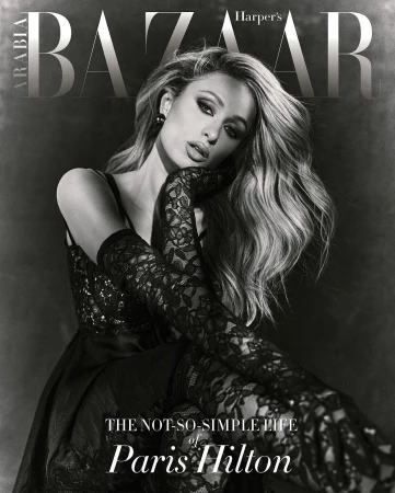 Paris Hilton poses in a black dress and lace gloves for a Harpers Bazaar Arabia cover. She has blonde hair and wears smokey eye makeup.