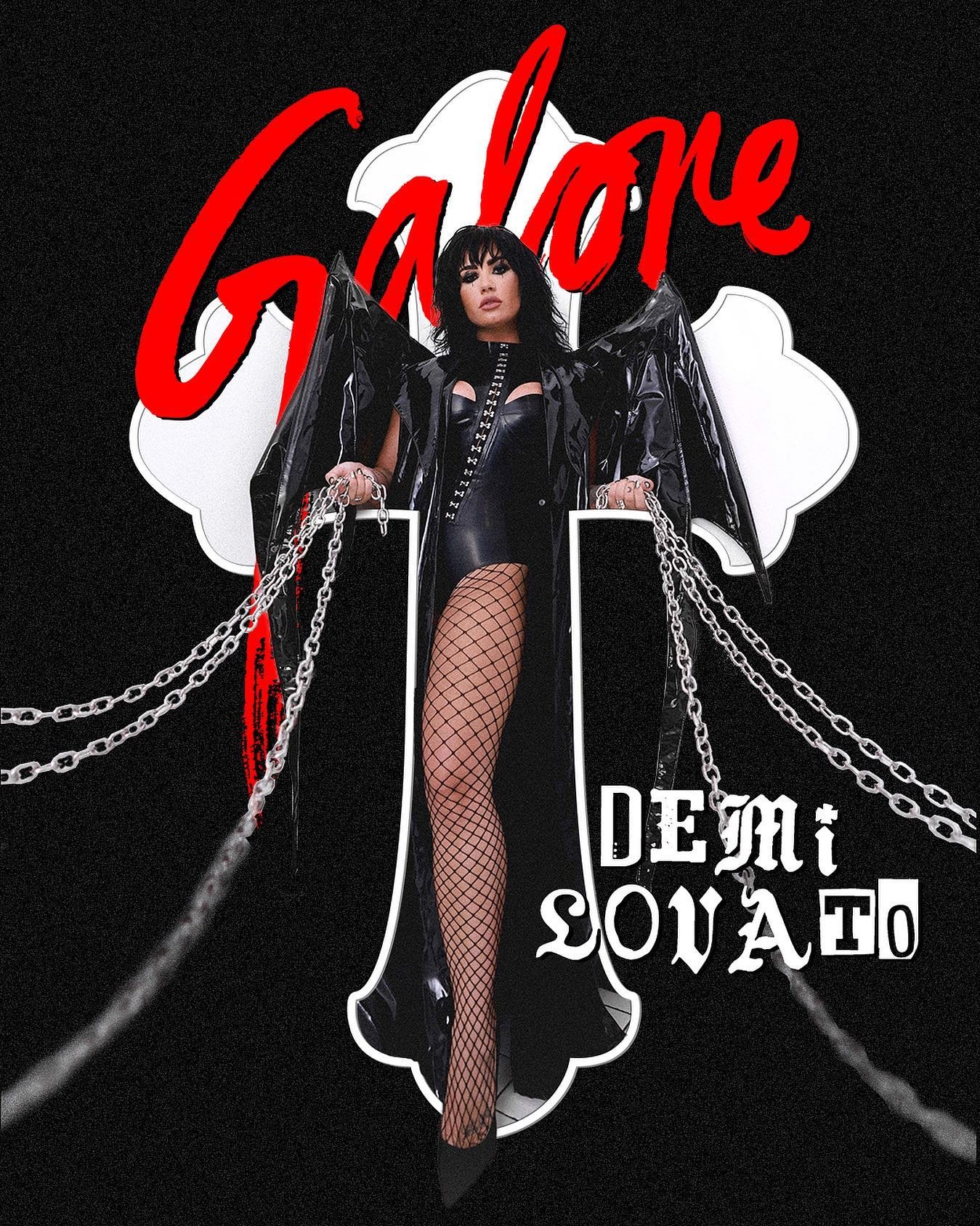 Demi Lovato poses in black vinyl outfit and fishnets with chains and a crucifix against a black background in a promotional shot.