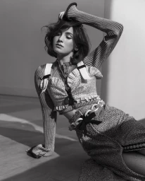 Monochrome portrait of a woman seated, wearing a ribbed sweater and textured skirt, photographed by Elias Tahan.