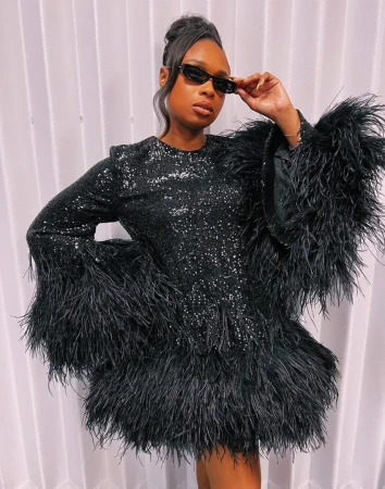 Jennifer Hudson wearing a black sequin dress with feathery cuffs and sunglasses, styled by Elizabeth Semande.
