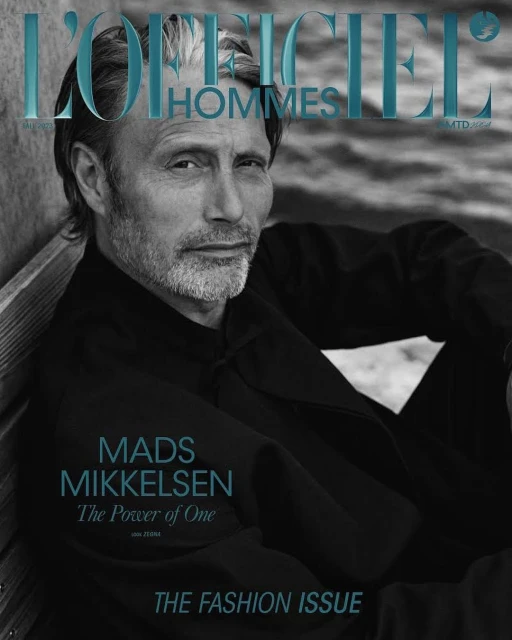 Magazine cover featuring Mads Mikkelsen in a dark jacket, striking a pose against a neutral backdrop. The title 'L'Officiel Hommes' is visible.