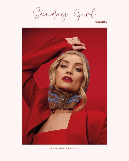 Magazine cover portrait featuring a woman in a red jacket and brown knit hood against a solid red background.