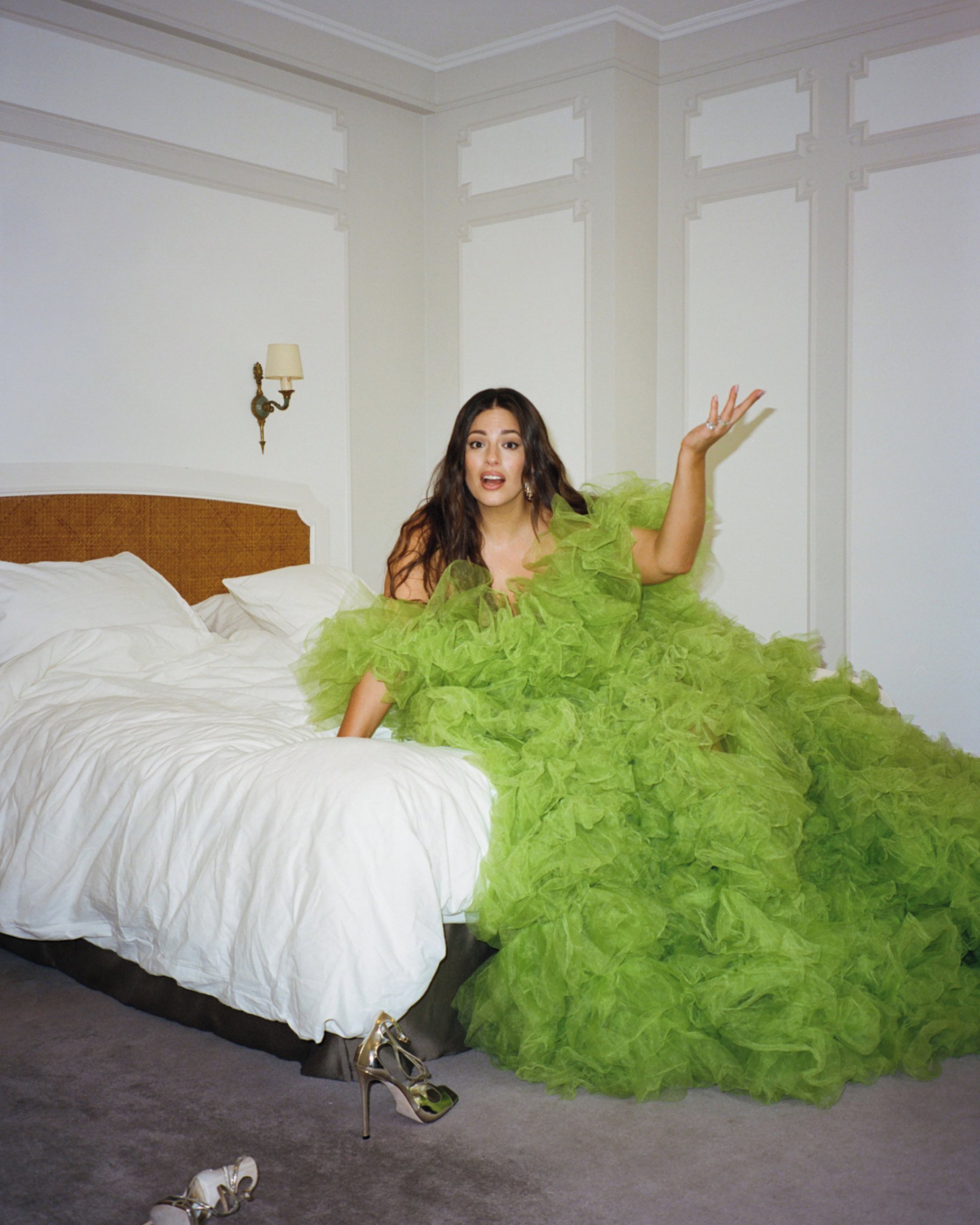 Plus-size model in green tulle gown on a hotel bed styled by Emma Lane