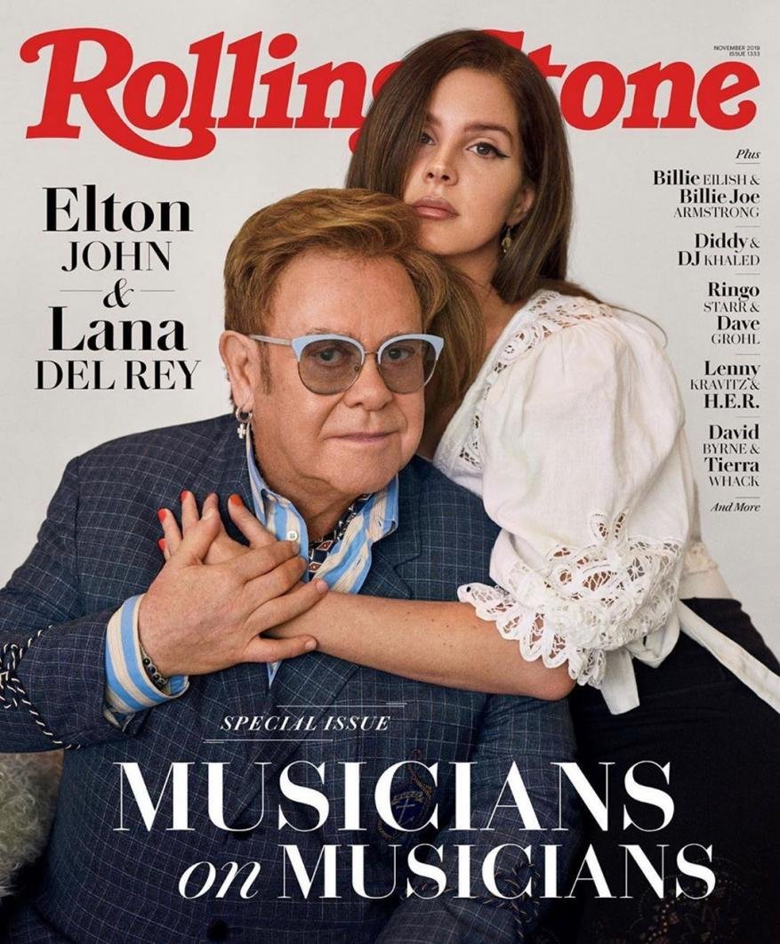 Elton John and Lana Del Rey pose for a Rolling Stone cover. The image features the pair in a close shot, with visible magazine text.