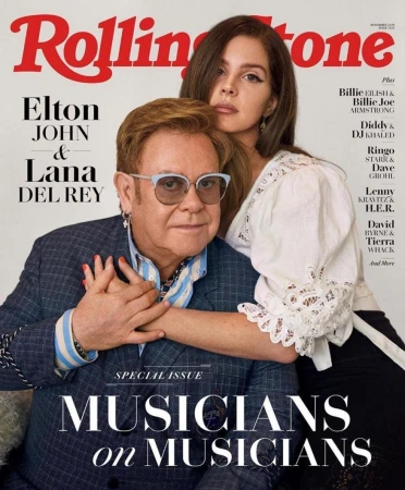 Elton John and Lana Del Rey pose for a Rolling Stone cover. The image features the pair in a close shot, with visible magazine text.