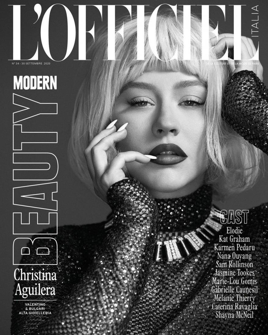 Black-and-white L'Officiel cover featuring Christina Aguilera in a shimmering dress, platinum wig, bold makeup, and manicured nails.