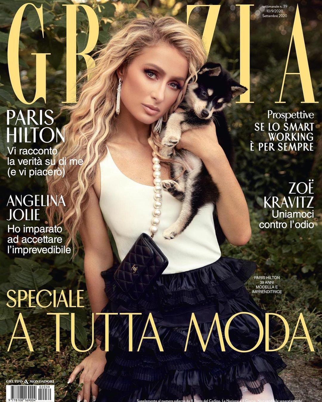 Magazine cover featuring Paris Hilton holding a puppy, wearing a white top and black skirt against an outdoor foliage background.