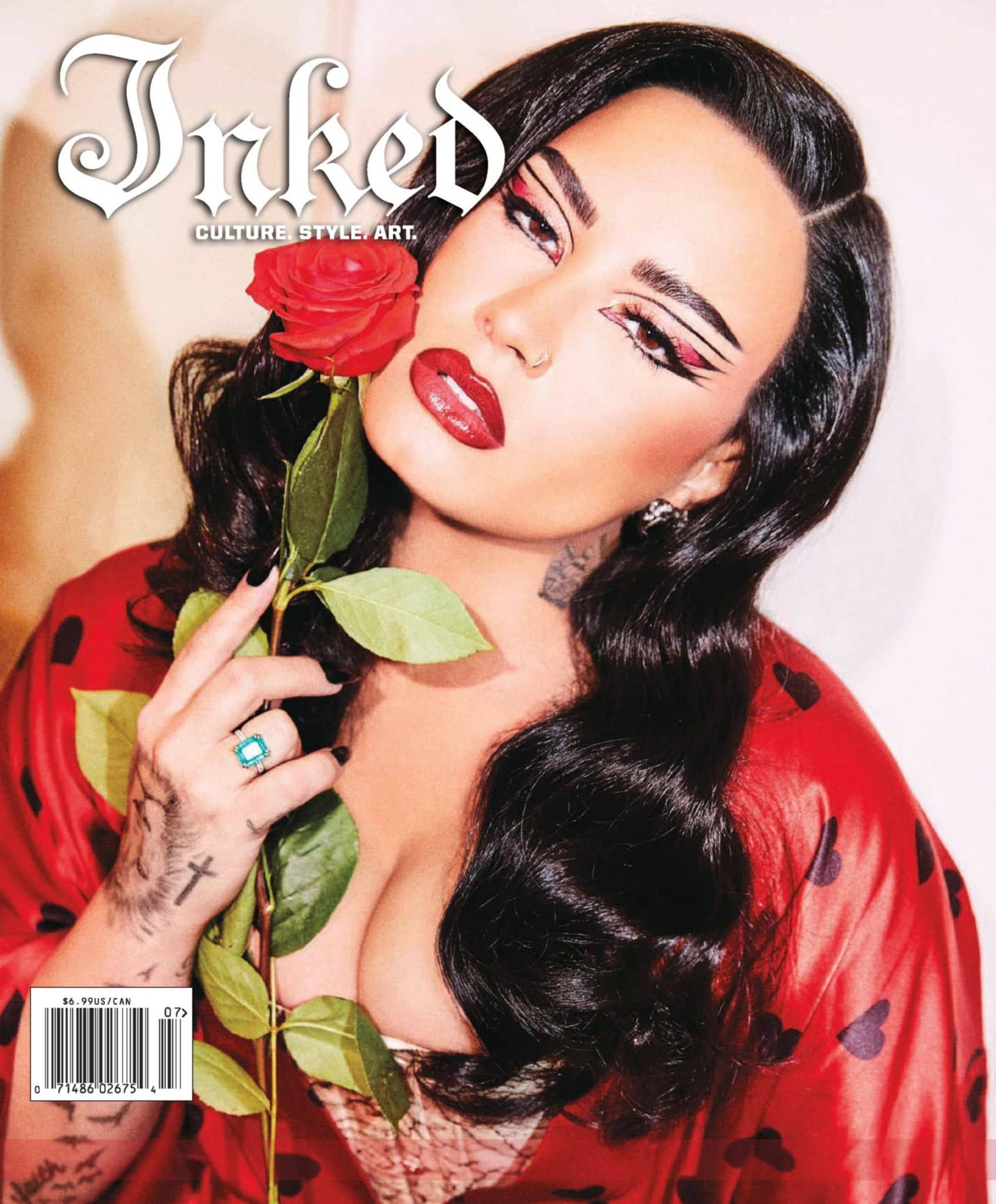 Magazine cover features a woman with bold makeup holding a red rose, wearing a red robe with hearts in a brightly lit studio.