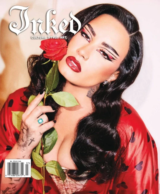 Magazine cover features a woman with bold makeup holding a red rose, wearing a red robe with hearts in a brightly lit studio.